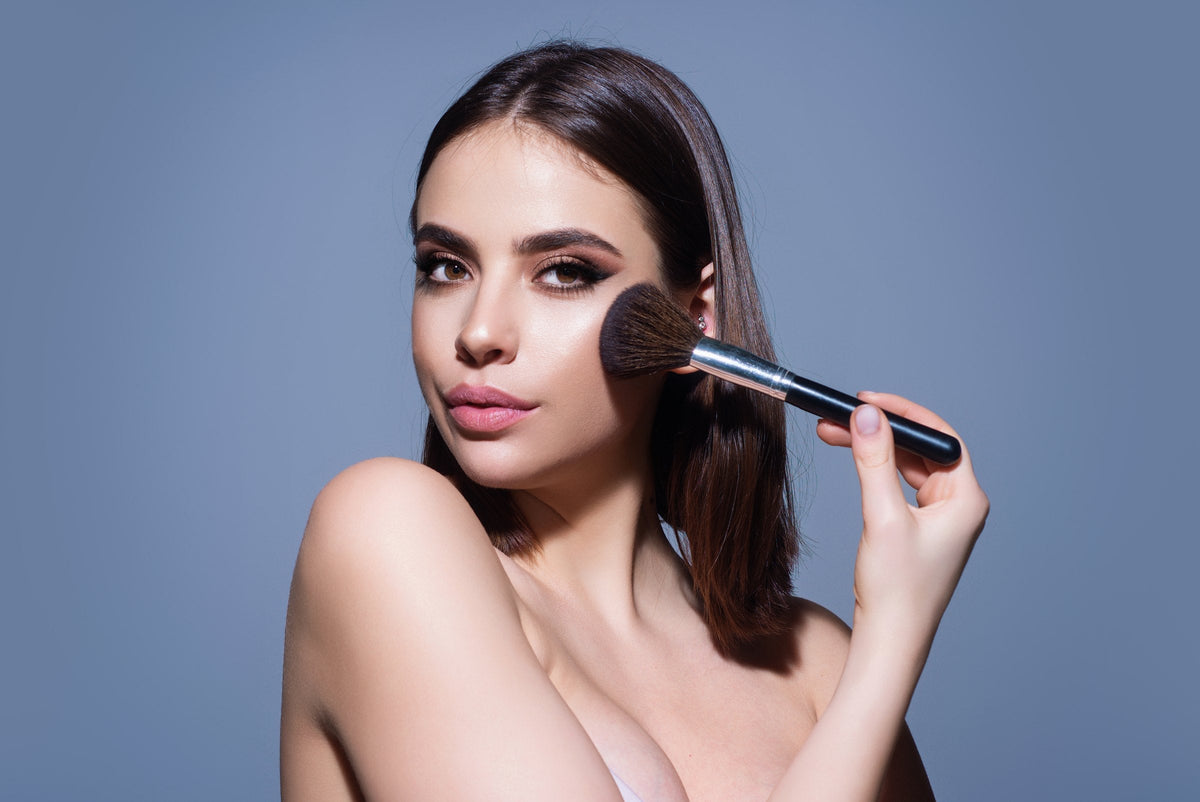 A woman sweeping powder onto her cheekbone with a make-up brush