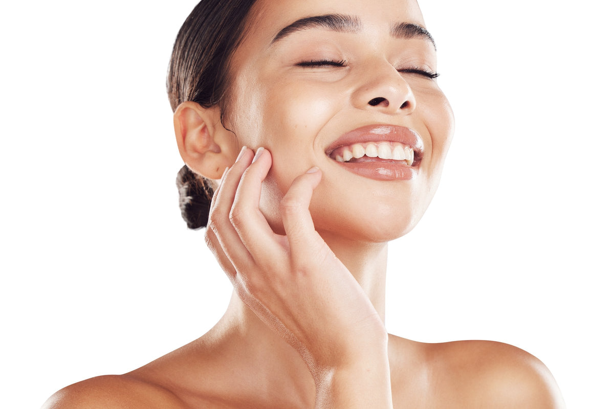 A smiling woman touching her clean, glowing skin