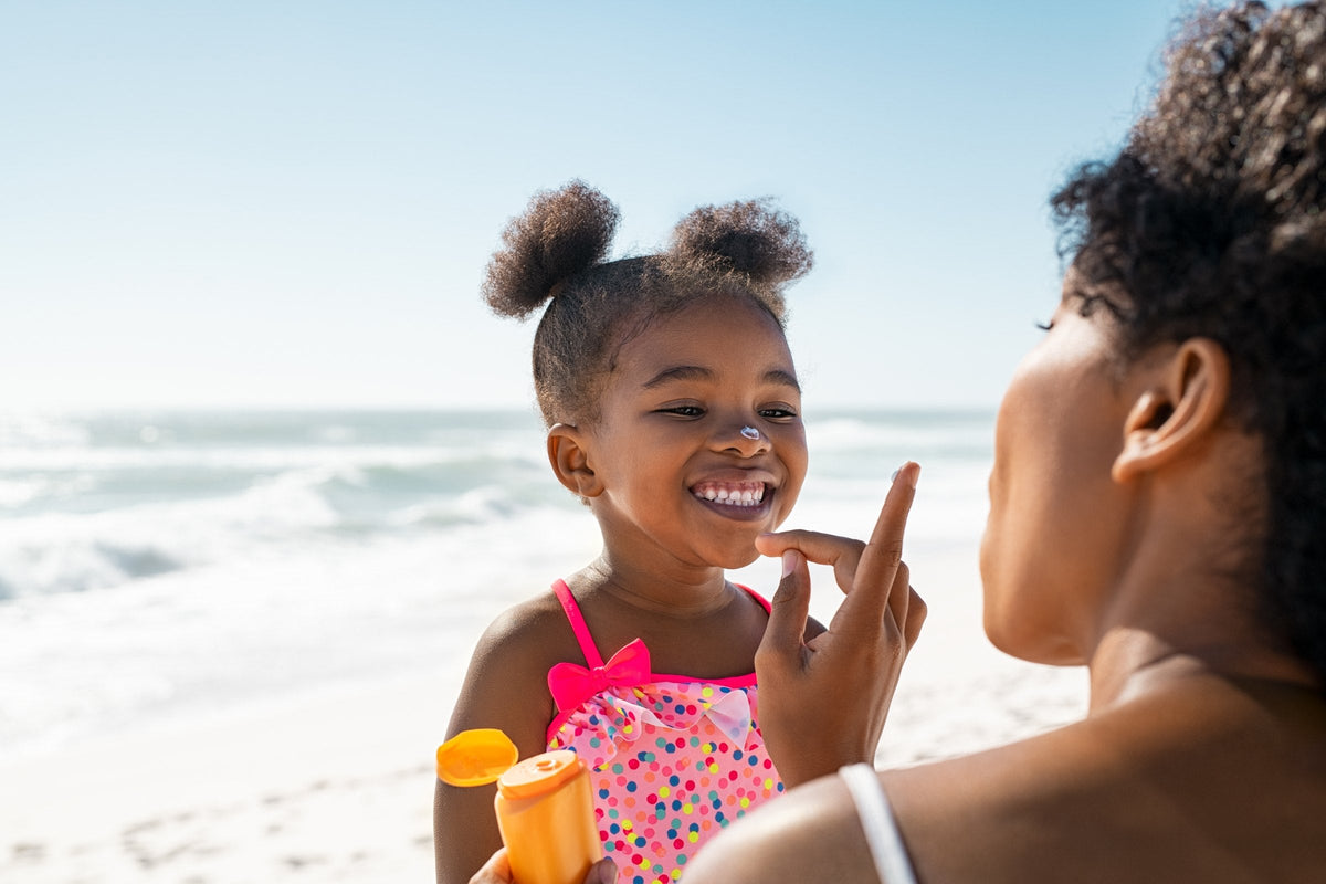 A mother applying sunscreen to her little girl's face