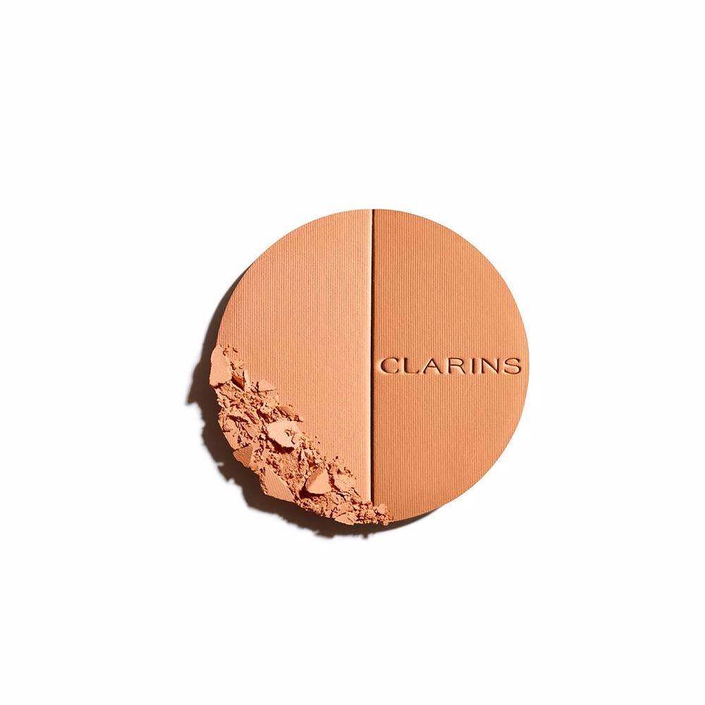 Clarins Round orange compact powder case with metallic rim, embossed brand name, minimalist metal/plastic finish