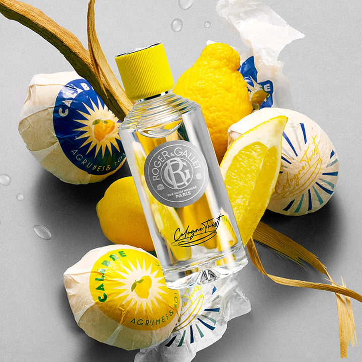 Roger &amp; Gallet Transparent glass cologne bottle with clear yellow liquid, ribbed yellow cap, round gray label, black cursive text, presented .