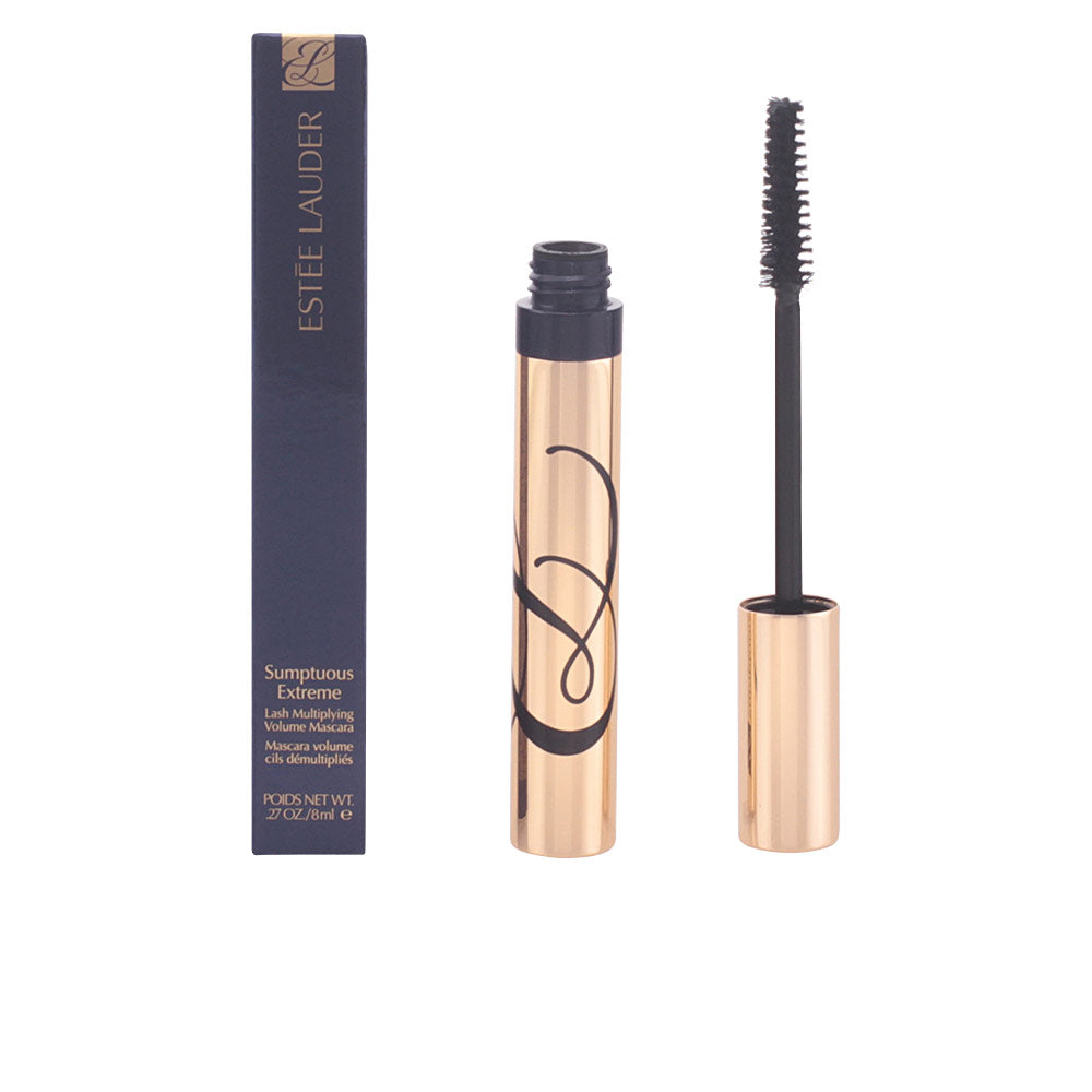 Estée Lauder Navy blue metallic cylindrical mascara tube with gold cap, black brush applicator beside rectangular box