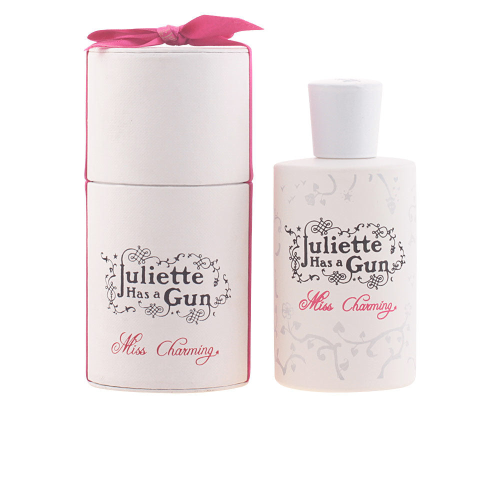 Juliette Has A Gun White and pink cylindrical box with floral vine pattern, bottle with cap and decorative ribbon