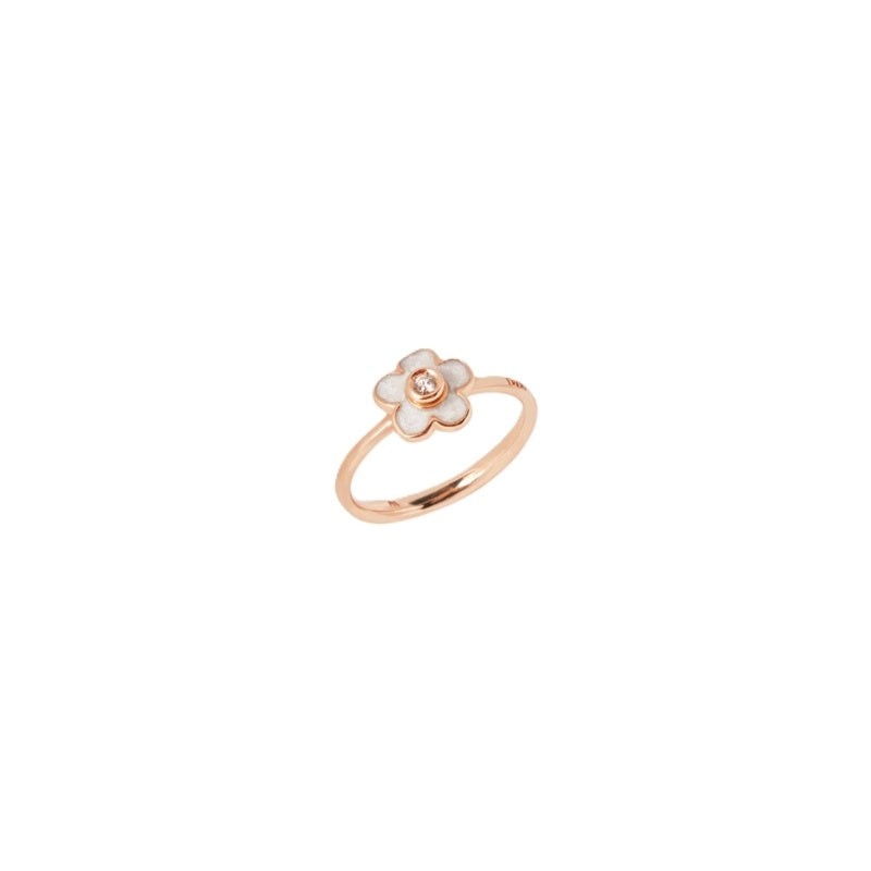 Rose gold flower ring with white enamel petals and central diamond on neutral background