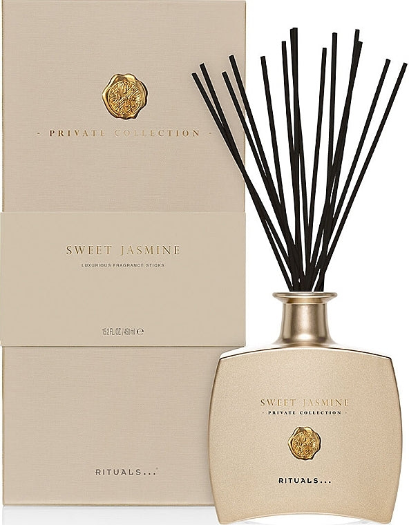 Rituals Glass reed diffuser with slender black reeds and amber liquid, citrus-berry floral notes visible in label